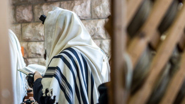 Jewish men praying in a synagogue with Tallit