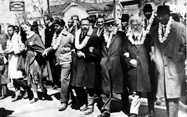 mlk jr and rabbi heschel walking together at the front of the parade