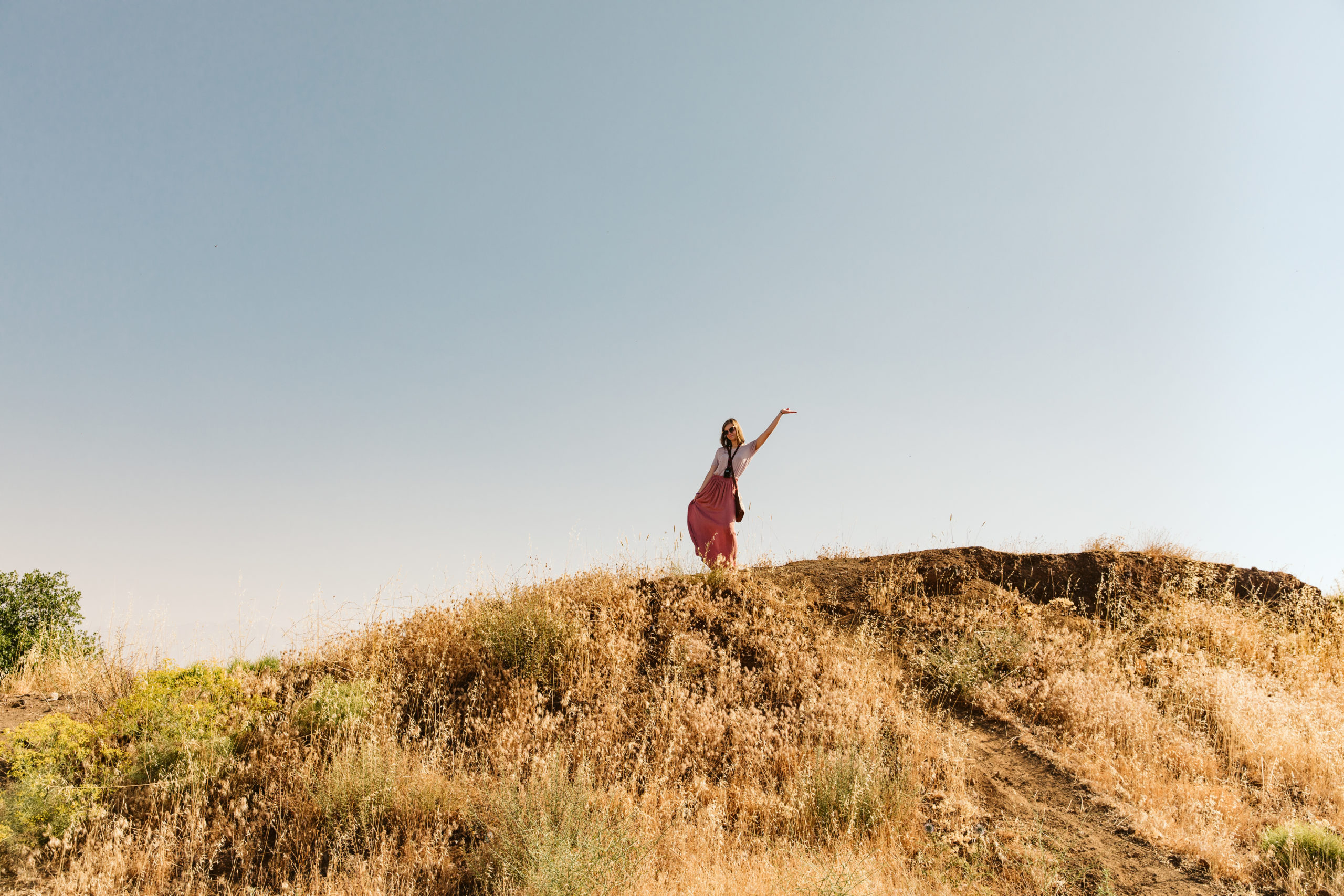 a girl waving from the top of a hill
