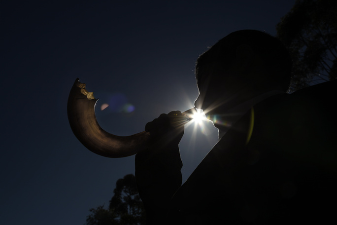 blowing a shofar in the moonlight