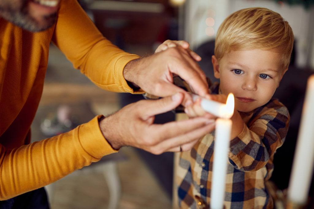 child lighting the candle with an adult