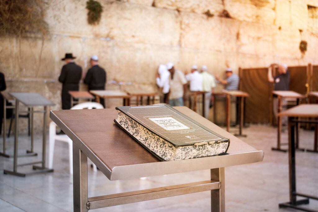 Jewish bible - Torrah on table on blurred background of praying Jews and wailing western wall. Israel. Jerusalem