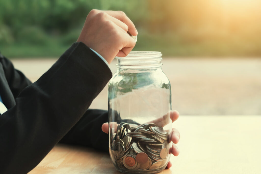 business hand putting coins in glass jar