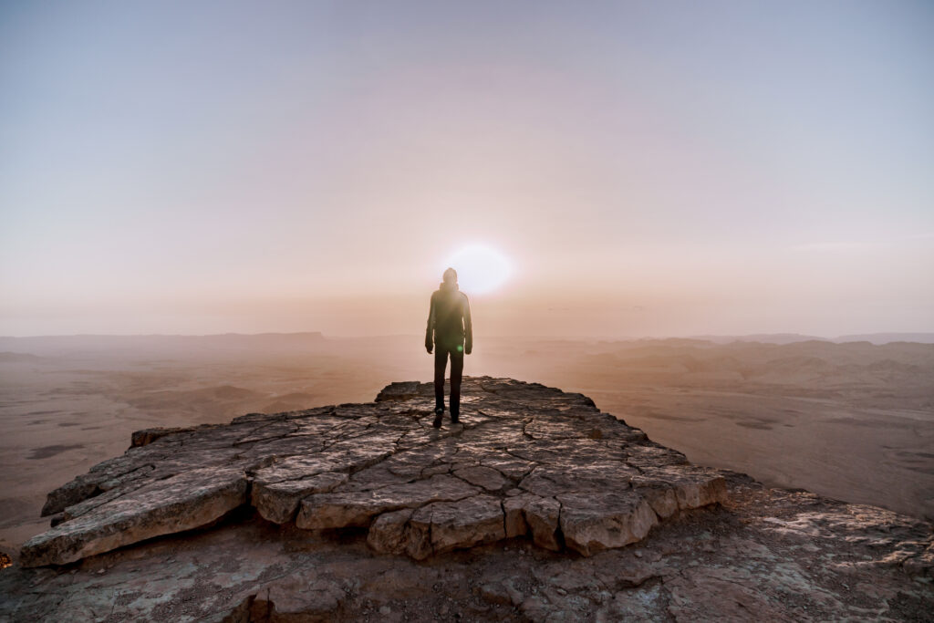 Alone man in israel negev desert admires the view of sunrise