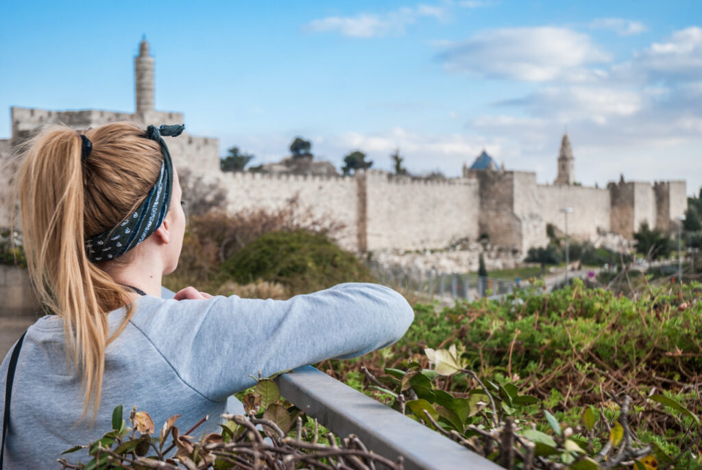A young woman praying for Jerusalem while looking at the Old City walls