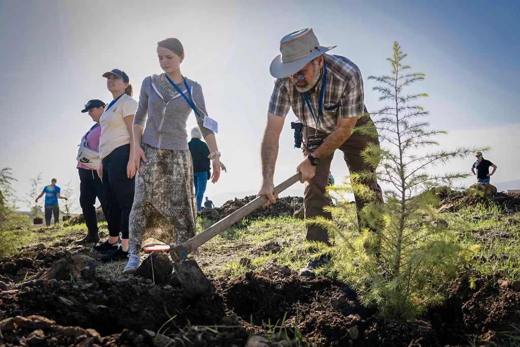 A man uses a gardening tool to help plant trees in Israel